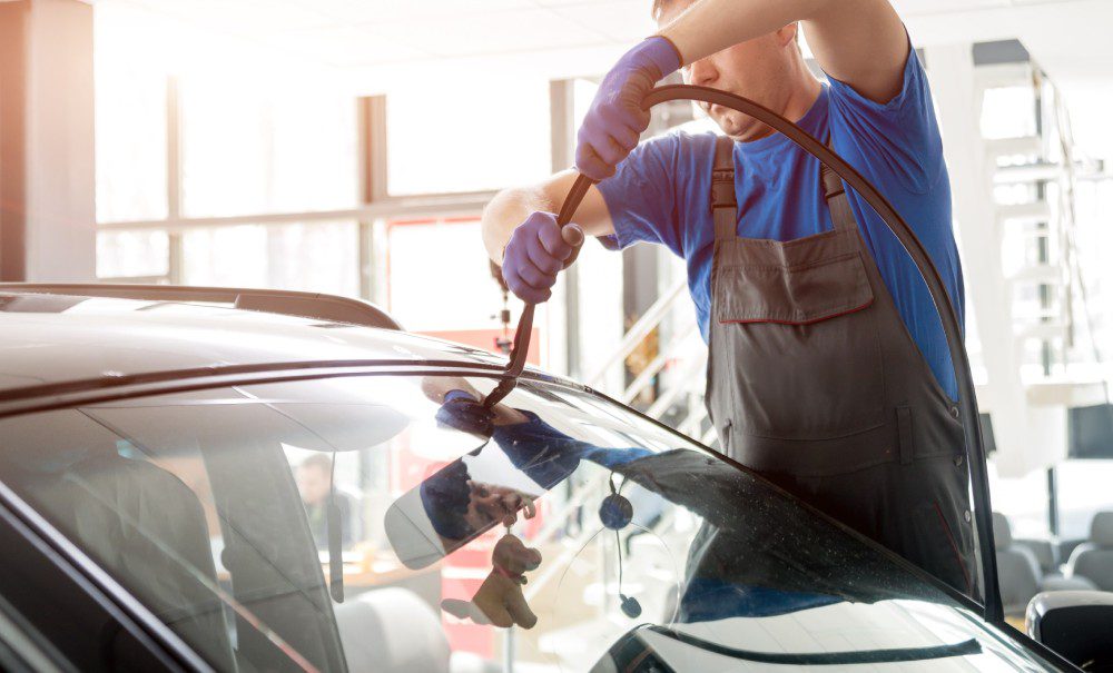 Automobile special workers remove old windscreen of a car in auto service